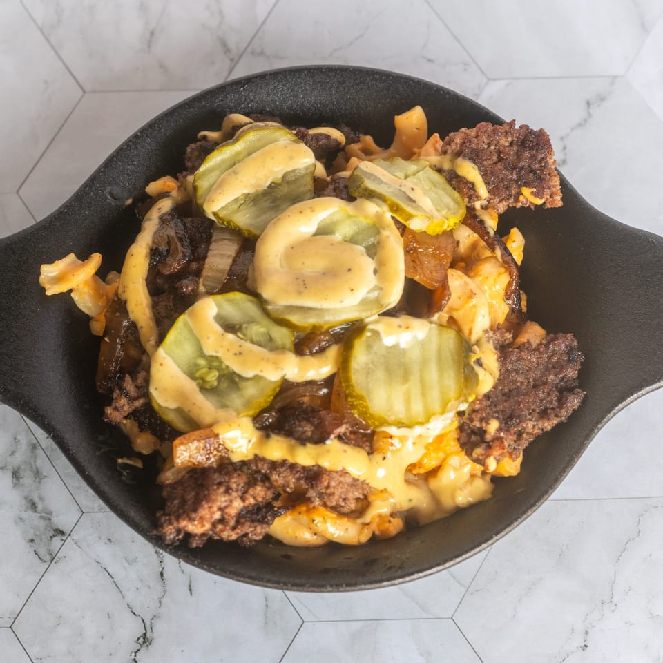 Loaded skillet of fries topped with crispy beef, pickles, sautéed onions, and creamy cheese sauce.