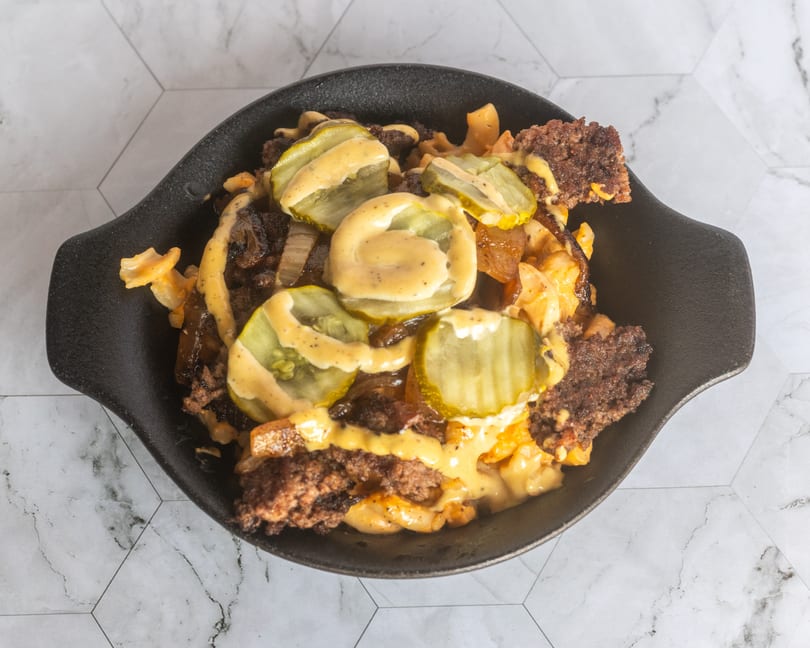 Overhead view of loaded fries topped with ground beef, pickles, and cheese sauce.